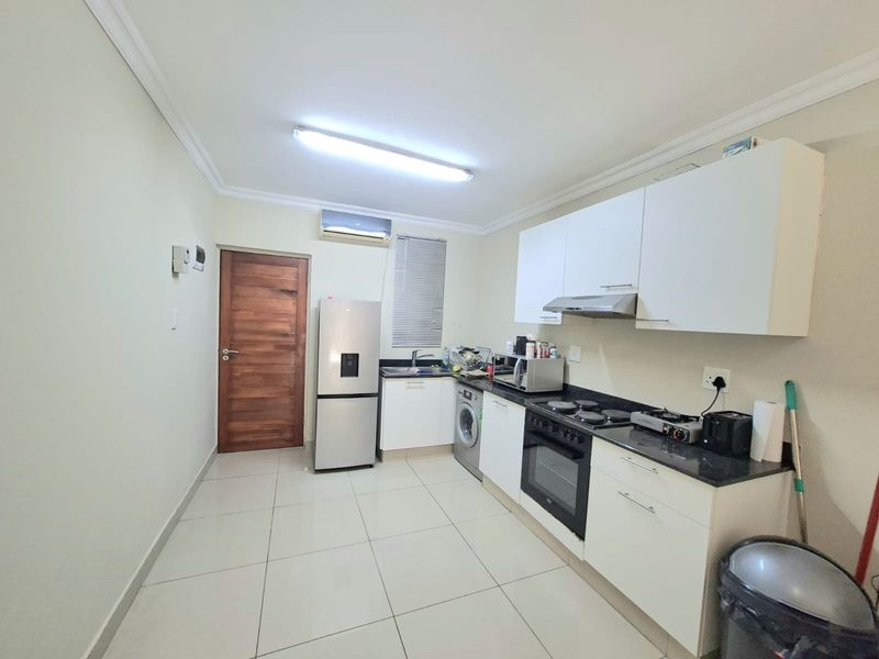 A functional kitchen featuring white cabinetry, granite countertops, built-in oven and hob, extractor fan, and tiled flooring.