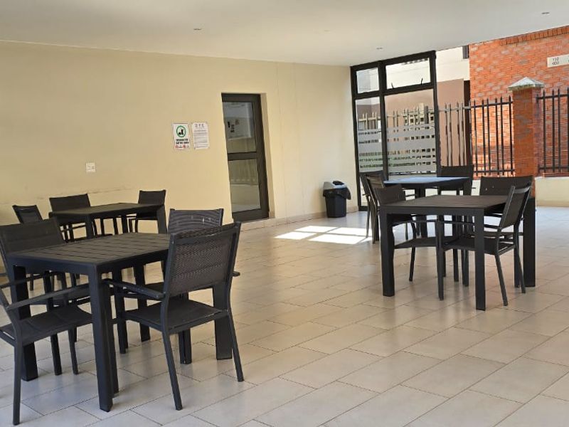 A spacious covered patio area featuring tiled flooring, built-in cabinetry with granite countertops, and secure metal fencing, ideal for outdoor entertaining.