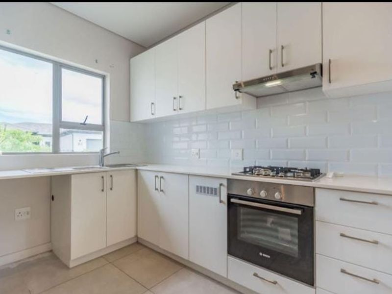 Modern kitchen featuring white cabinetry, subway tile backsplash, stainless steel oven, gas hob, and extractor fan with ample counter space.