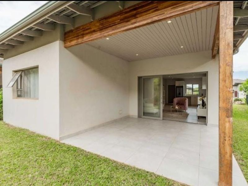 A covered patio area featuring tiled flooring, timber structural beams, and recessed lighting, providing seamless access to the interior through sliding glass doors.
