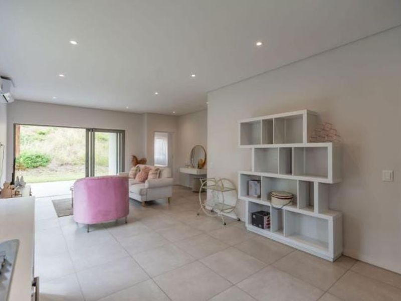 Spacious open-plan living area featuring large format floor tiles, recessed downlights, and seamless access to the outdoor space through sliding glass doors.