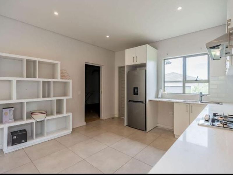 Modern kitchen featuring white cabinetry, gas hob, extractor fan, and tiled flooring, offering a clean and functional workspace.