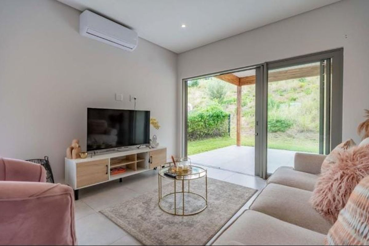 Modern living room featuring tiled floors, a wall-mounted air conditioner, and large sliding glass doors providing seamless access to the outdoor patio area.