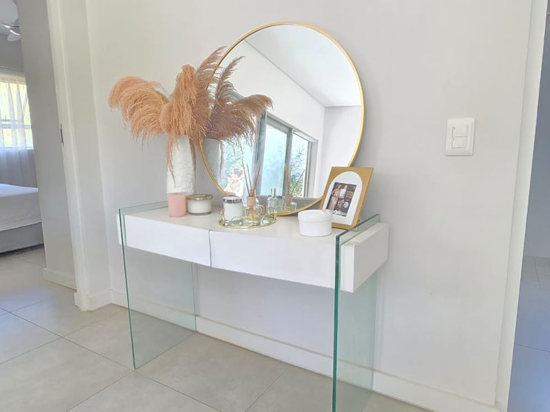 A bright and neutral hallway featuring clean tiled flooring and access to adjacent bedroom and bathroom areas.