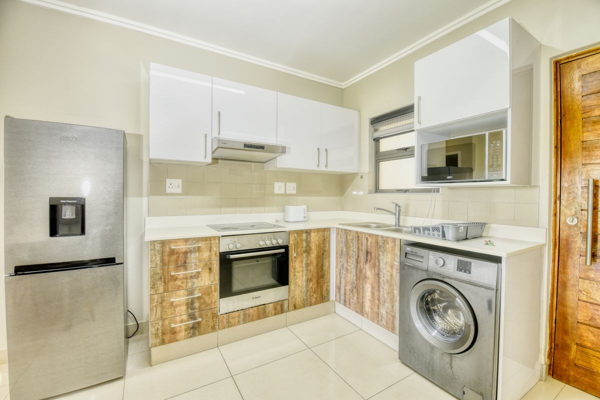 Modern kitchen featuring white and wood-grain cabinetry, integrated appliances, tiled backsplash, and sleek tiled flooring.