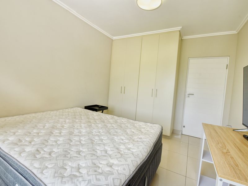 A well-maintained bedroom featuring neutral walls, tiled flooring, and ample built-in cupboard storage space.