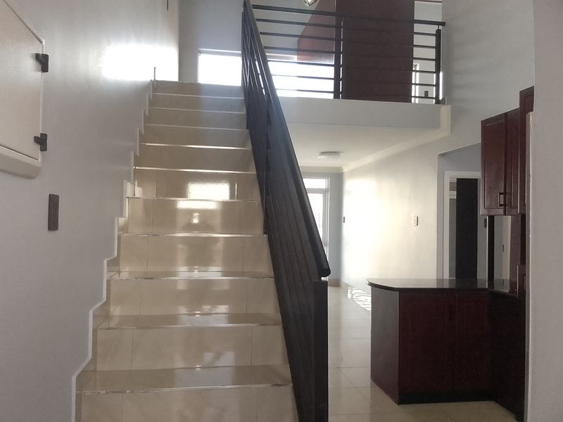 Entrance area featuring a tiled staircase with metal balustrade, leading to a mezzanine level, with adjacent built-in cabinetry and stone countertop.