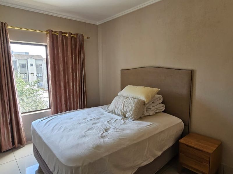 A standard bedroom featuring tiled flooring and a built-in cupboard, providing a functional living space with natural light.