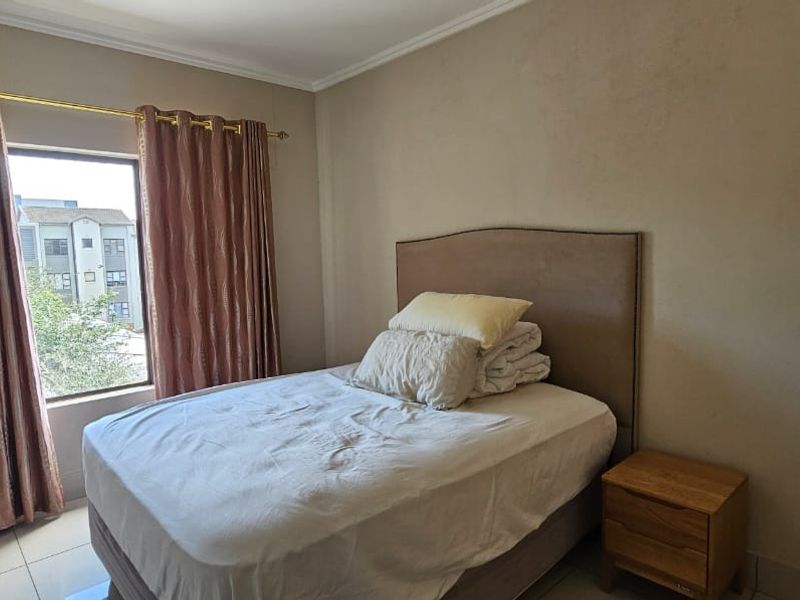 A functional bedroom featuring tiled flooring, a built-in wardrobe, and a window with natural light, offering a neutral base for personalization.