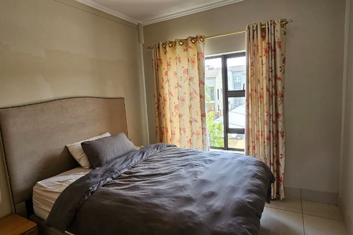 A bedroom featuring tiled flooring and a window, currently showing signs of wall paint wear and surface imperfections.