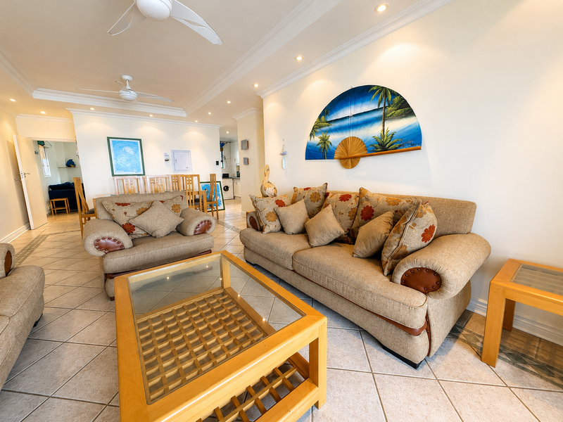 Spacious open-plan living area featuring tiled flooring, recessed lighting, and ceiling fans, with a seamless flow toward the dining and kitchen spaces.