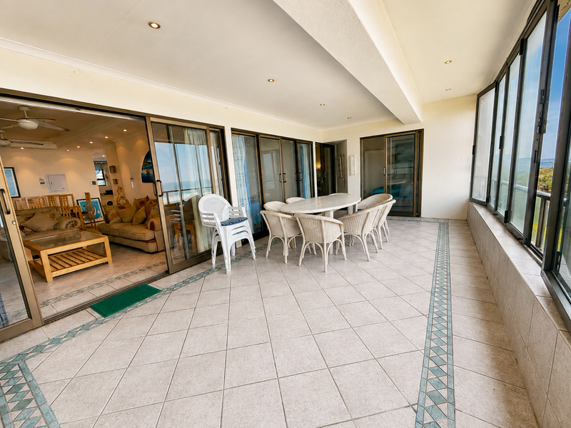 Spacious covered balcony featuring tiled flooring, recessed lighting, and large sliding glass doors providing seamless access to the interior living area.