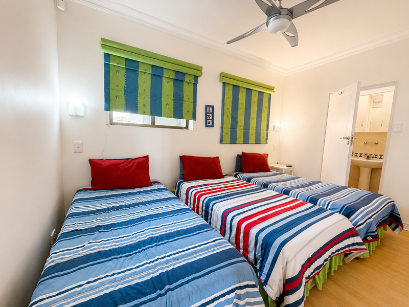 A bedroom featuring laminate flooring, a ceiling fan, and direct access to an en-suite bathroom.