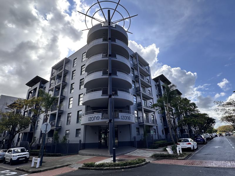 Exterior view of a modern apartment building featuring a distinctive cylindrical architectural design with stacked balconies and street-level access.