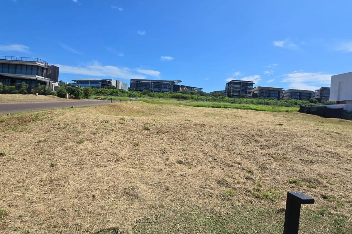 A vacant residential plot of land situated in a developed estate, featuring road access and surrounding modern residential properties.