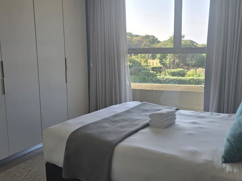 A well-maintained bedroom featuring built-in cupboards, tiled flooring, and a large window offering pleasant natural light and views.