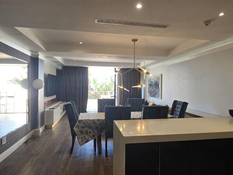 Modern open-plan living and dining area featuring a kitchen island, recessed ceiling lighting, ducted air conditioning, and high-quality laminate flooring.