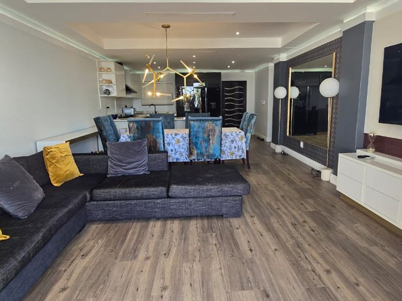Spacious open-plan living and dining area featuring modern laminate flooring, recessed ceiling lighting, and a contemporary layout suitable for entertaining.
