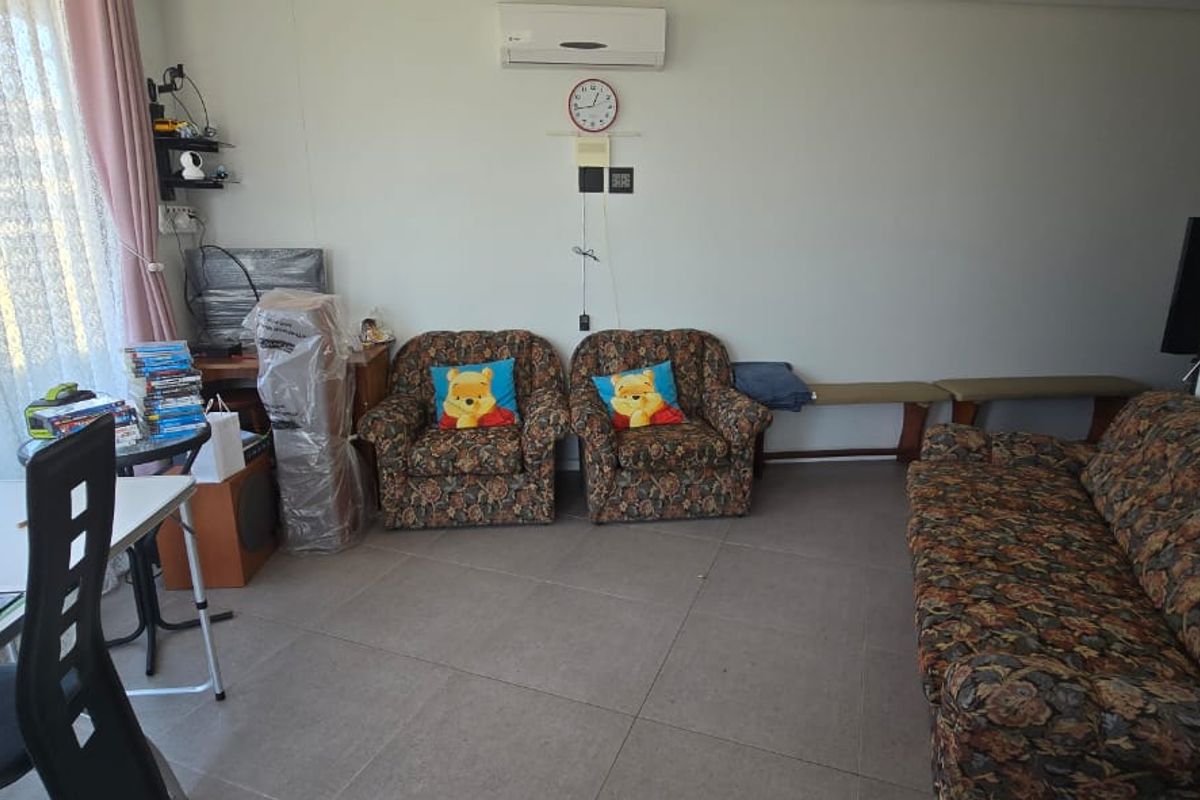 A living room area featuring tiled flooring, a wall-mounted split-system air conditioner, and access to a balcony through a sliding glass door.
