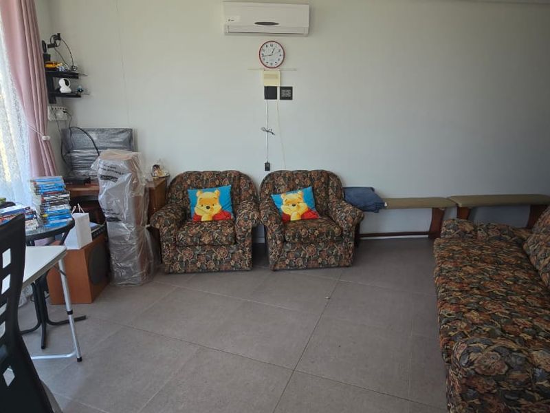 A living room area featuring tiled flooring, a wall-mounted split-system air conditioner, and access to a balcony through a sliding glass door.