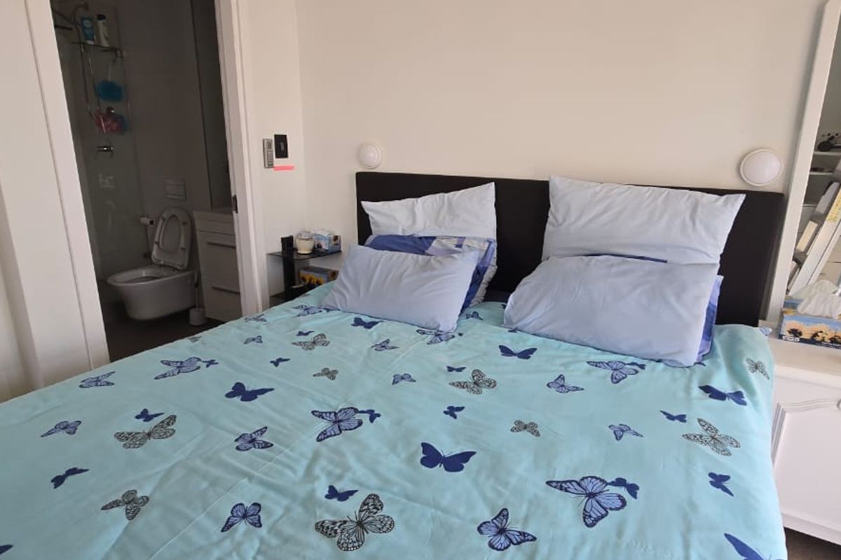 A bedroom featuring a built-in headboard, wall-mounted lighting, and direct access to an en-suite bathroom.