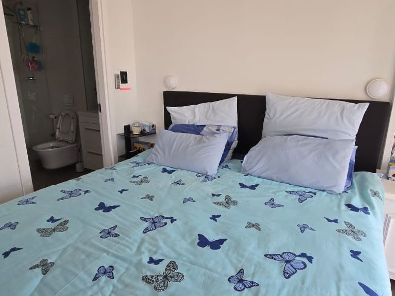 A bedroom featuring a built-in headboard, wall-mounted lighting, and direct access to an en-suite bathroom.