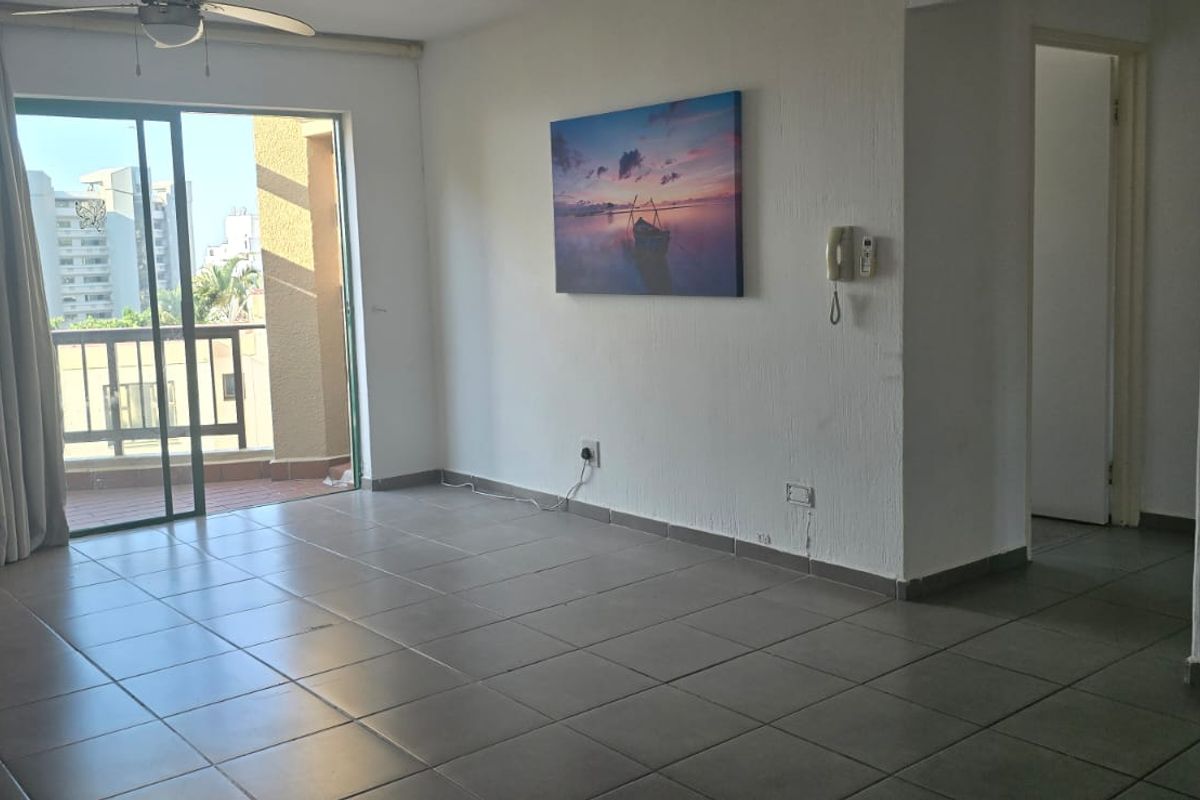 Spacious living area featuring tiled flooring, a ceiling fan, and a sliding glass door leading to a balcony.