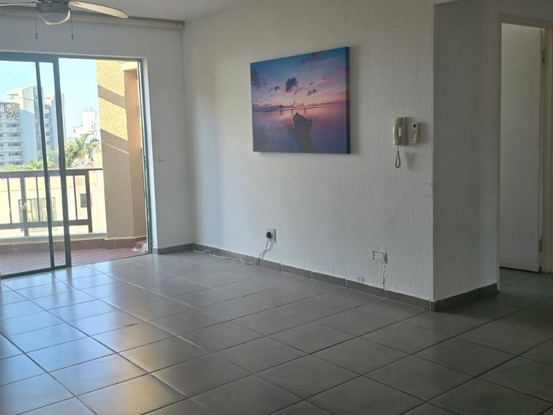 Spacious living area featuring tiled flooring, a ceiling fan, and a sliding glass door leading to a balcony.