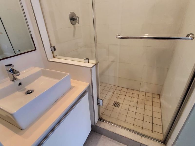 A functional bathroom featuring a modern vessel sink, vanity cabinet, and a glass-enclosed shower with tiled finishes.