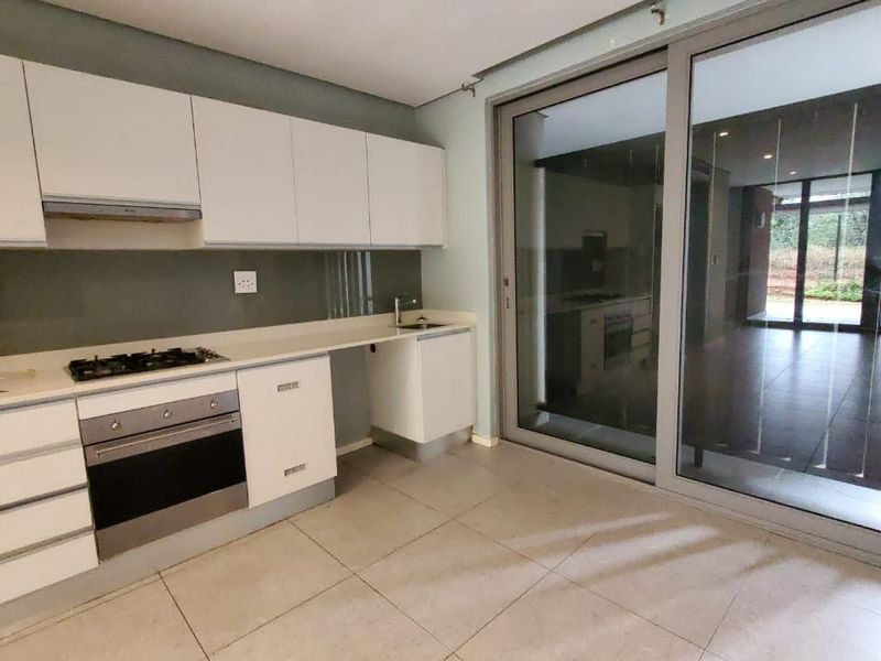 Modern kitchen featuring white cabinetry, gas hob, built-in oven, and large sliding glass doors leading to an outdoor area.