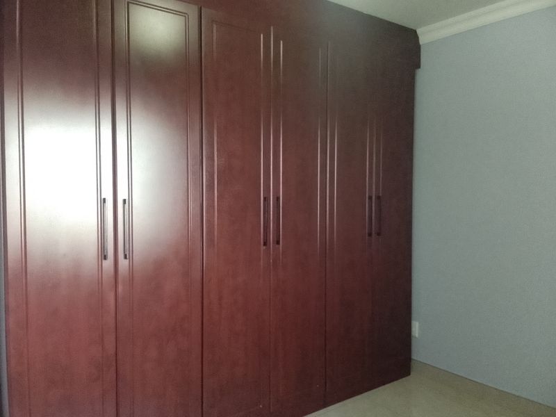 A bedroom featuring extensive dark wood built-in cupboards with vertical detailing and crown molding, providing ample storage space.