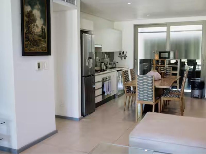 Open-plan living and kitchen area featuring modern cabinetry, integrated appliances, tiled flooring, and large sliding glass doors leading to an outdoor space.