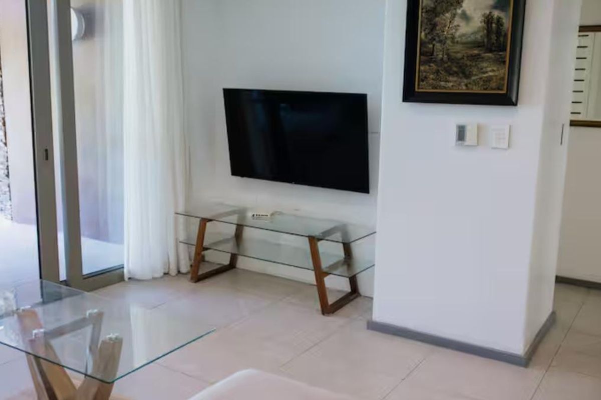 A bright living room featuring tiled flooring and a large sliding glass door providing access to an outdoor area.