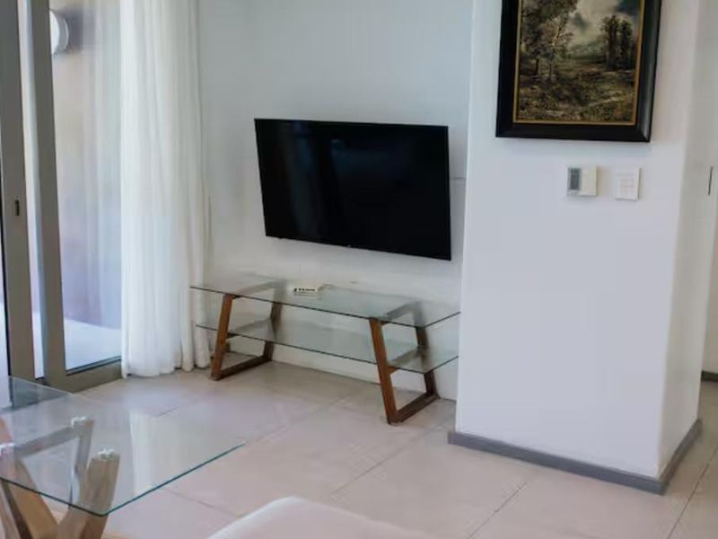 A bright living room featuring tiled flooring and a large sliding glass door providing access to an outdoor area.