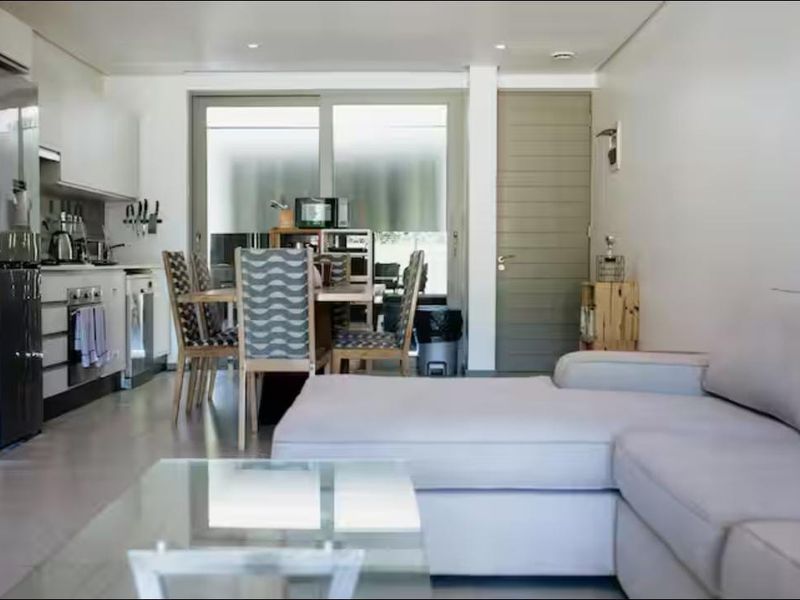 Open-plan living area featuring a modern kitchen with built-in appliances, tiled flooring, and sliding glass doors leading to an outdoor space.