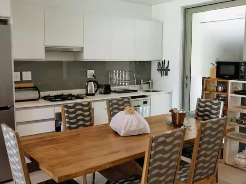 Modern open-plan kitchen and dining area featuring sleek white cabinetry, a gas hob, and direct access to an outdoor patio through a sliding door.