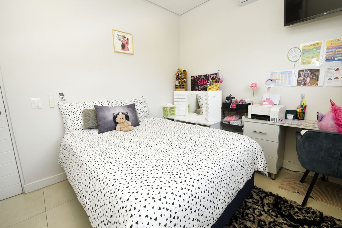 A well-maintained bedroom featuring tiled flooring, a built-in desk area, and an integrated air conditioning unit.
