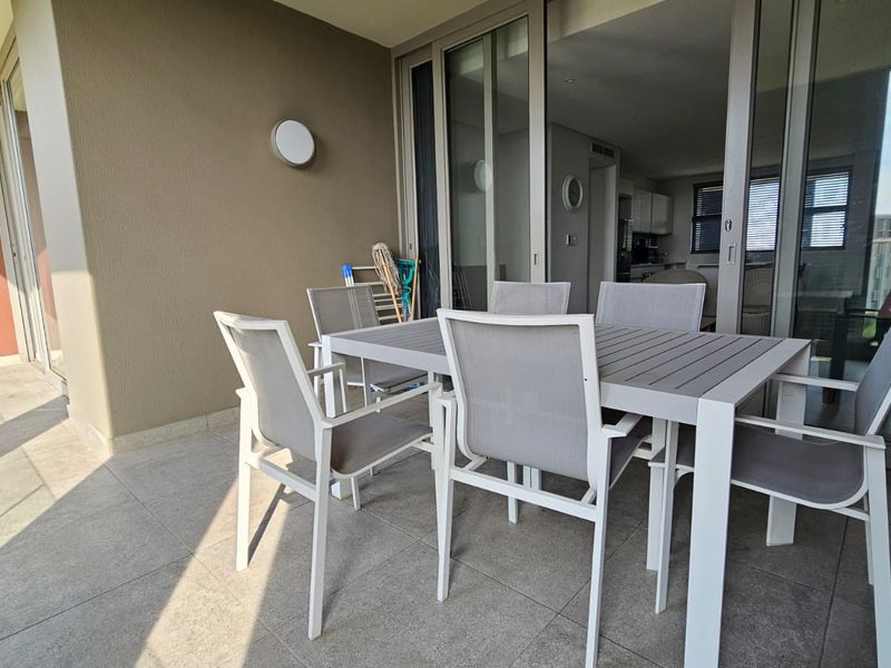 A spacious covered balcony featuring tiled flooring and large sliding glass doors that provide seamless access to the interior living area.