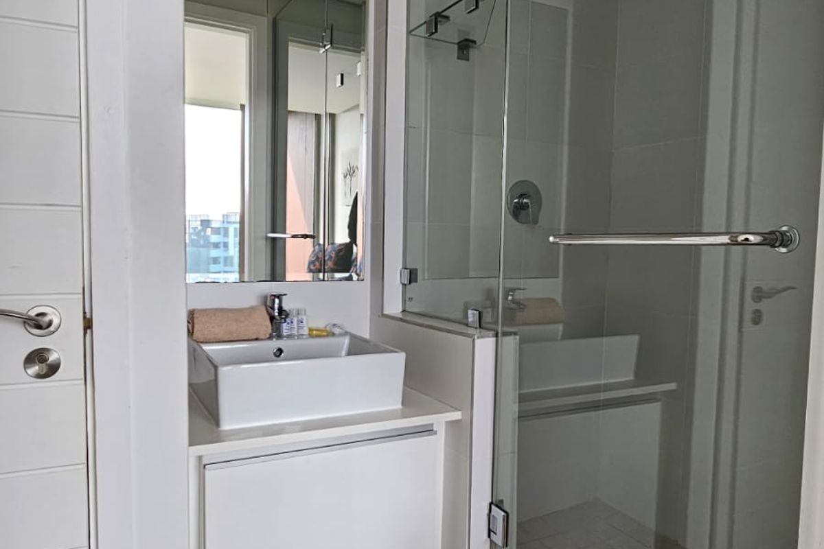 Modern bathroom featuring a vessel sink vanity, glass-enclosed shower, and neutral tiled finishes, offering a clean and contemporary aesthetic.
