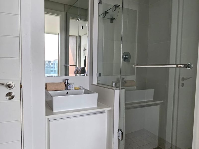 Modern bathroom featuring a vessel sink vanity, glass-enclosed shower, and neutral tiled finishes, offering a clean and contemporary aesthetic.