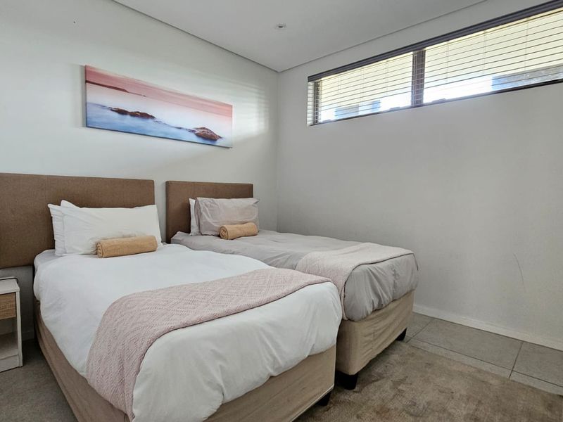A well-maintained bedroom featuring tiled flooring, built-in cupboards, and horizontal blinds, providing a clean and functional living space.