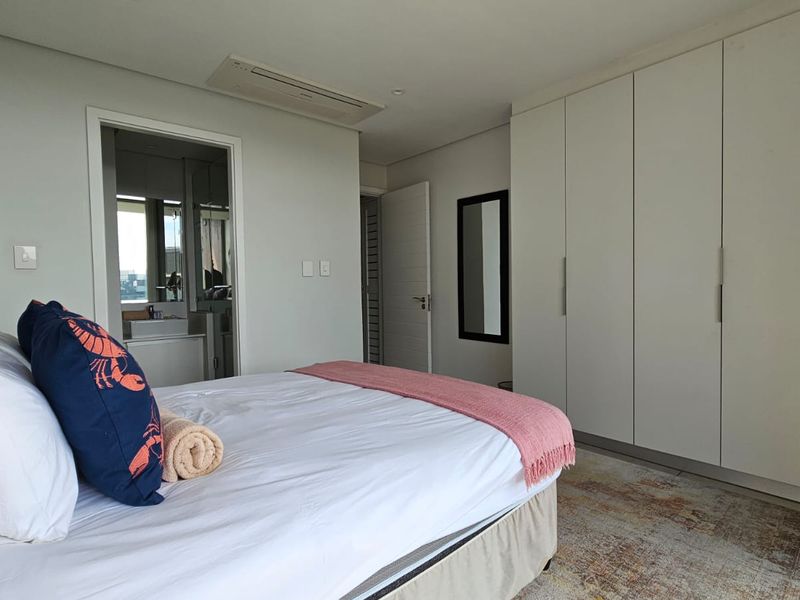 A well-maintained bedroom featuring built-in cupboards, ducted air conditioning, and direct access to an en-suite bathroom.