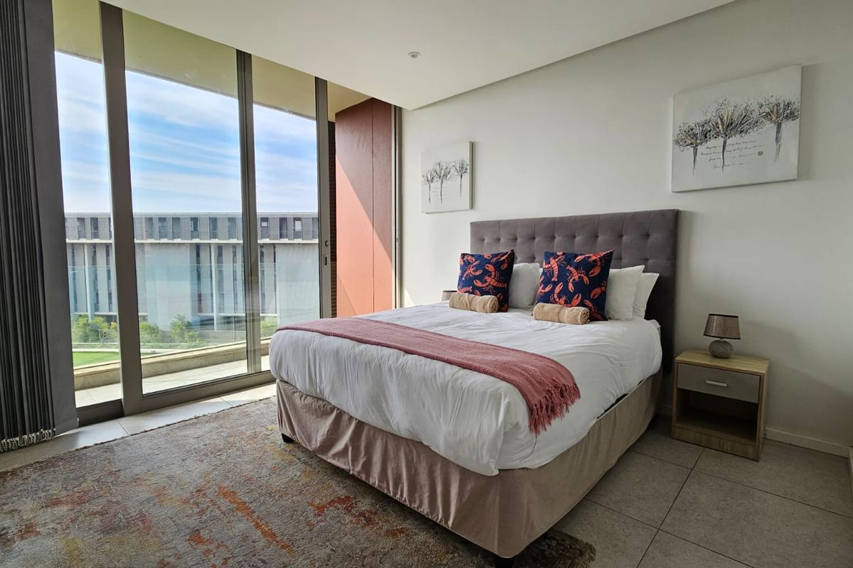 A bright, modern bedroom featuring large floor-to-ceiling sliding glass doors that provide ample natural light and access to an outdoor area.