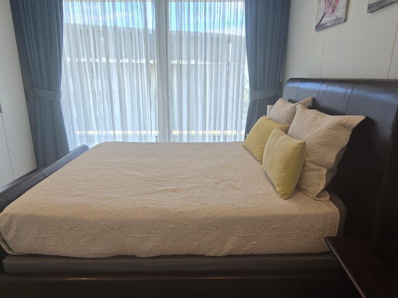 A well-maintained bedroom featuring built-in wardrobes, tiled flooring, and large windows with curtains allowing for natural light.