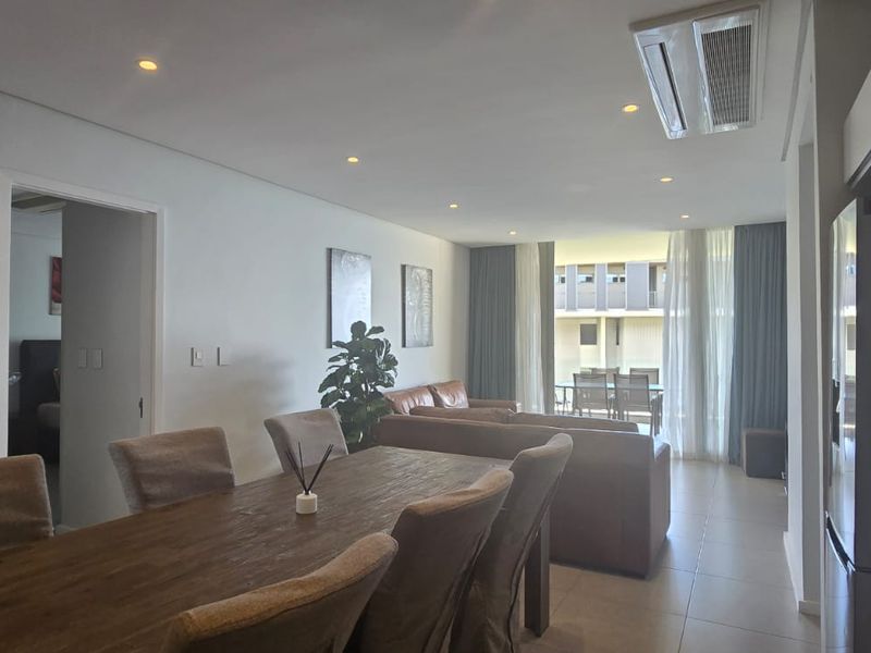 Spacious open-plan living and dining area featuring tiled floors, recessed lighting, ducted air conditioning, and seamless access to a private balcony.