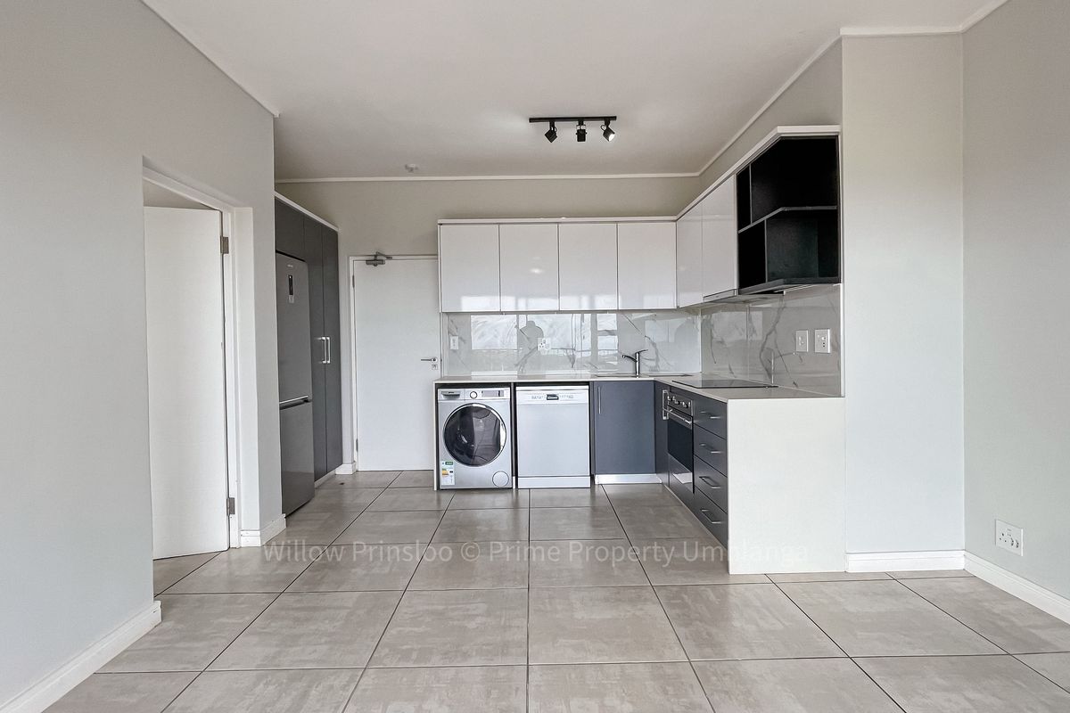 Modern kitchen featuring sleek two-tone cabinetry, stone countertops, integrated appliances, and neutral tiled flooring in an open-plan layout.