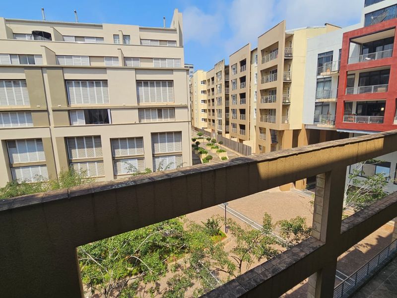 A view from a balcony overlooking a paved courtyard and surrounding apartment complex buildings.