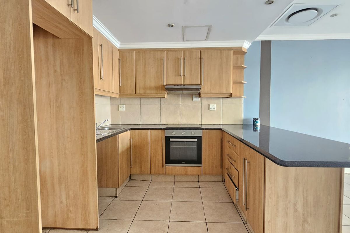 A functional kitchen featuring light wood cabinetry, granite countertops, integrated oven, and a breakfast bar, offering a clean and practical layout.
