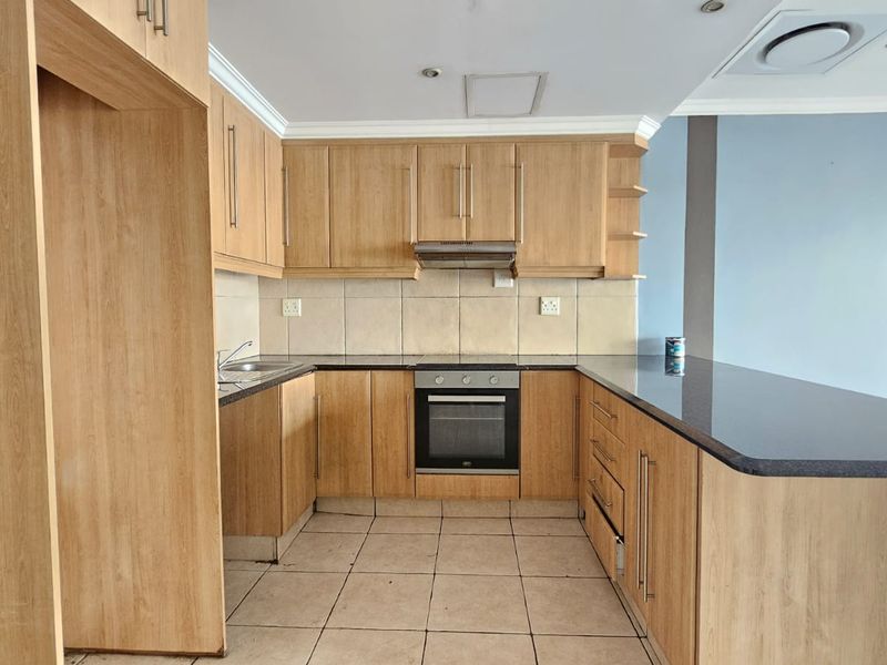 A functional kitchen featuring light wood cabinetry, granite countertops, integrated oven, and a breakfast bar, offering a clean and practical layout.