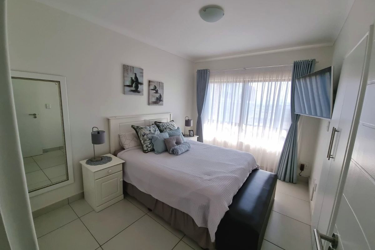 A well-maintained bedroom featuring neutral tiled flooring, a built-in cupboard, and large windows with natural light.
